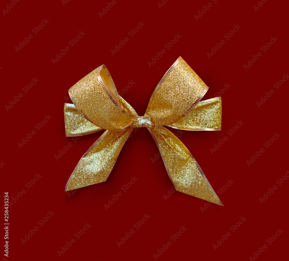 golden glittery bow on red background