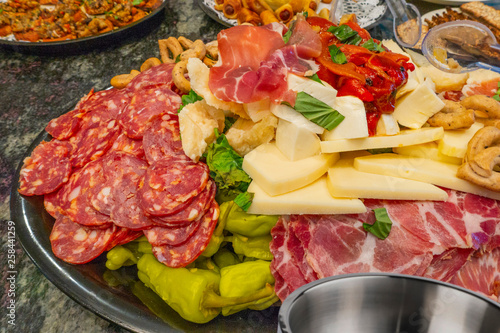 Antipasto food on a steel tray plater with cheeses  Prosciutto, Provolone, Sopressata, Manchego, pickled peppers cooked peppers