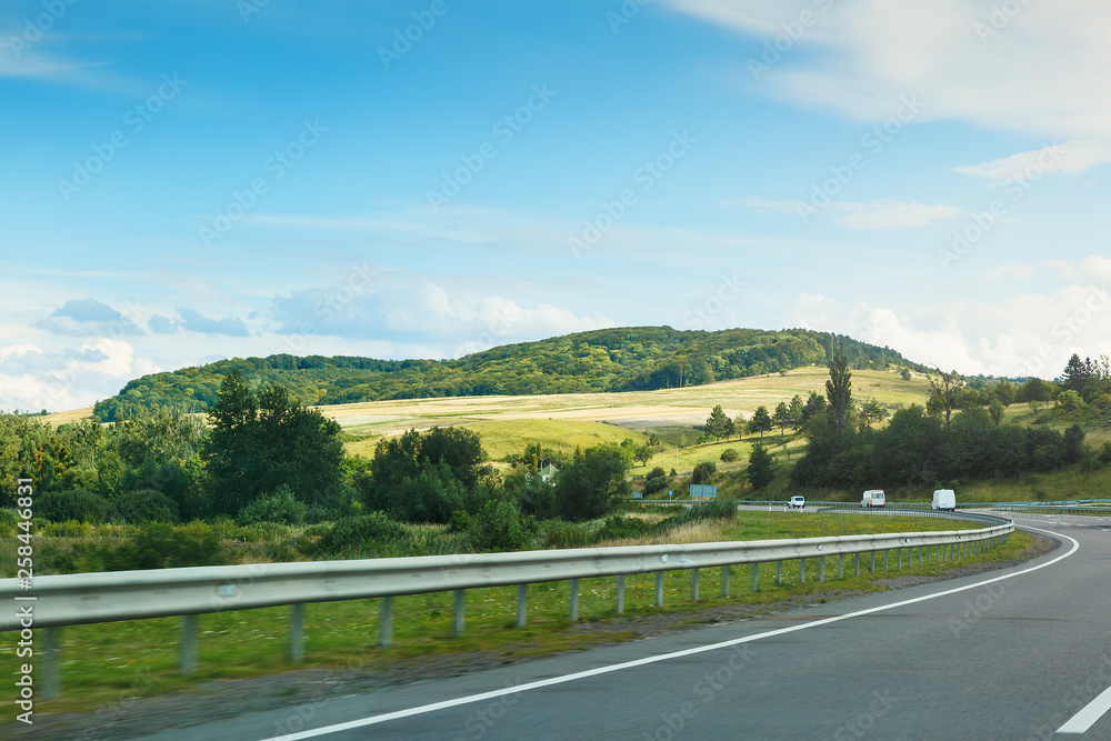 The empty asphalt road and blue sky with white clouds on the sunny day. Classic panorama view of road through fields and hills 