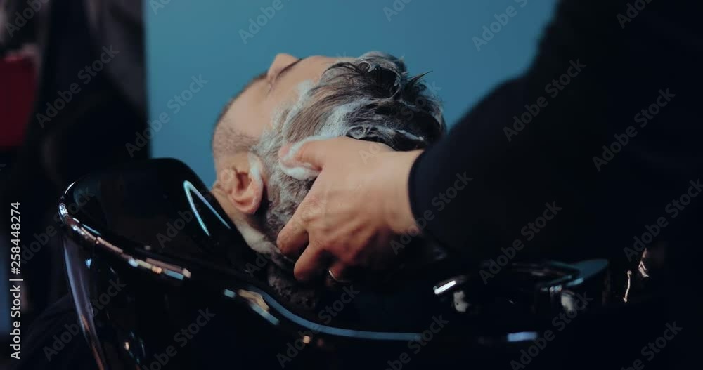 Vidéo Stock Hairdresser shampooing client's hair, a lot of foam on his