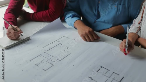 Young people studying new blueprints at office. Close up shot of architects with paper plan. Concept of architecture plan