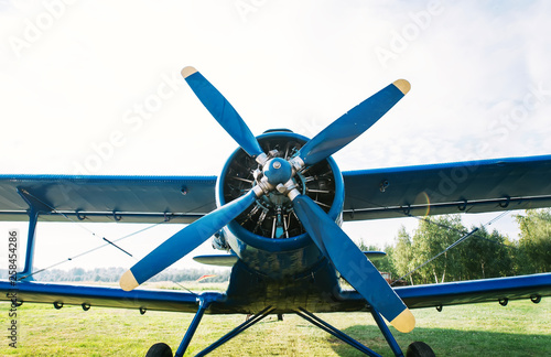 Small plane with propeller on a background of green grass and clear sky.
