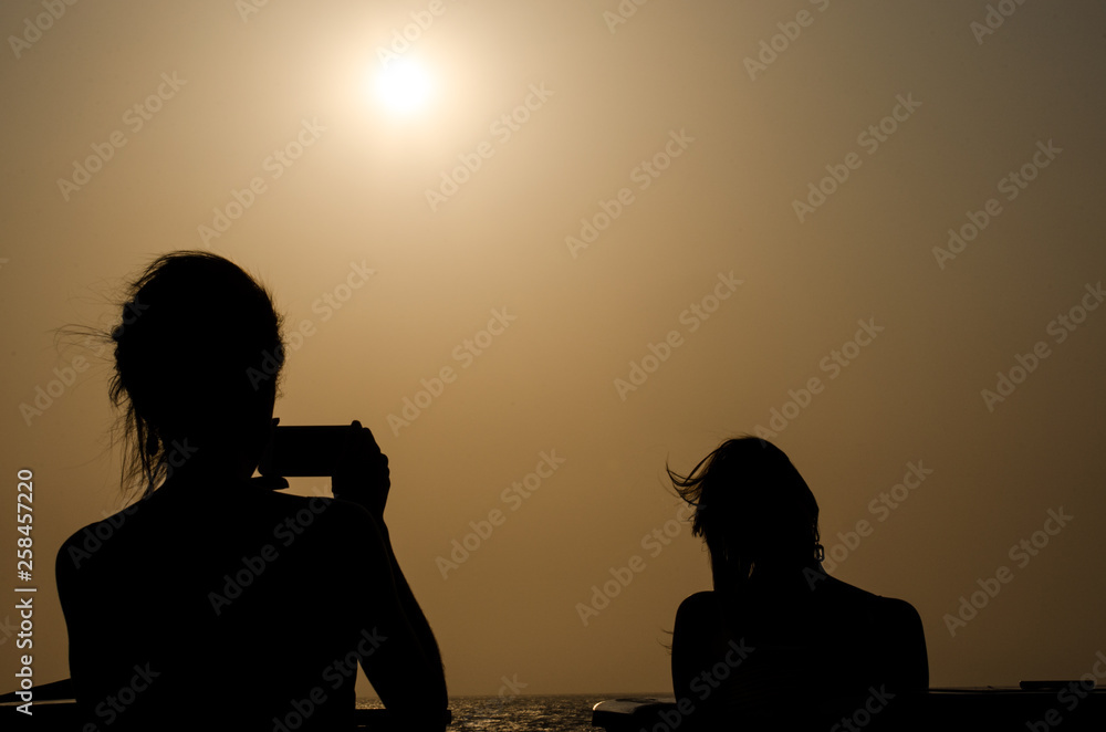 silueta de dos mujeres tomando una foto al atardecer