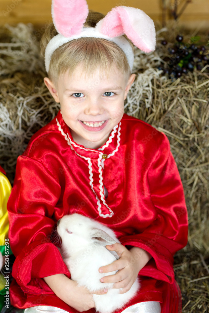little boy plays with white Easter Bunny. on the green grass and baby bunnies, Spring Festival and birth. little boy plays with white Easter Bunny. on the green grass and baby bunnies, Spring Festival and birth.