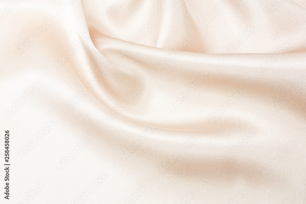 The texture of the satin fabric of beige color for the background The texture of the satin fabric of beige color for the background