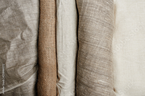 Natural fabrics from organic colors of flax and cotton in rolls, homespun textile handmade. Burlap and canvas for eco, rustic, boho, hygge decor photo