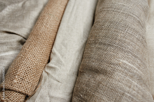 Natural fabrics from organic colors of flax and cotton in rolls, homespun textile handmade. Burlap and canvas for eco, rustic, boho, hygge decor