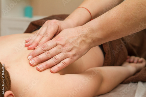 the masseur gives the child a back massage