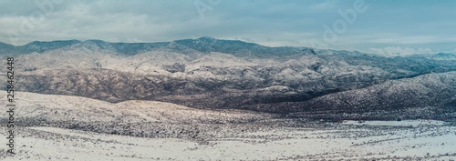 The mountains of Arizona in winter with Snow. This panorama has three distinct layers of mountains with dramatic clouds.