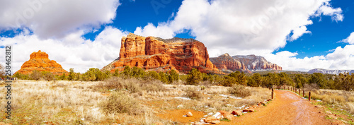 The red rock mountains of Arizona with a red dirt trail leading the viewer to the distant mountains.  The bright puffy clouds and blue sky of the wild west desert invites the viewer to walk into the s photo