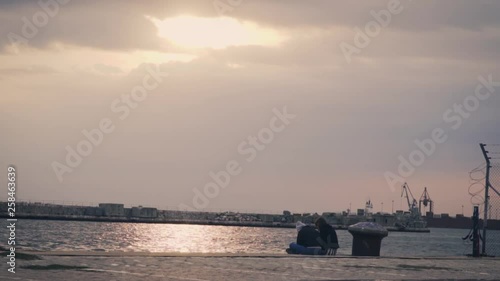 Thessaloniki / Greece 28 march 2019 :girls are  seating in the road by the sea they enjoy the good weather and the sunset