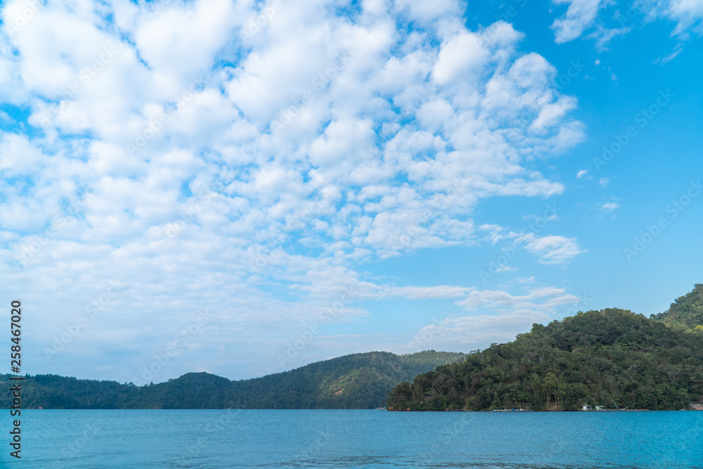 Mountains landscape scene with blue sky and white clouds over green water in sun moon lake in Taipei, Taiwan