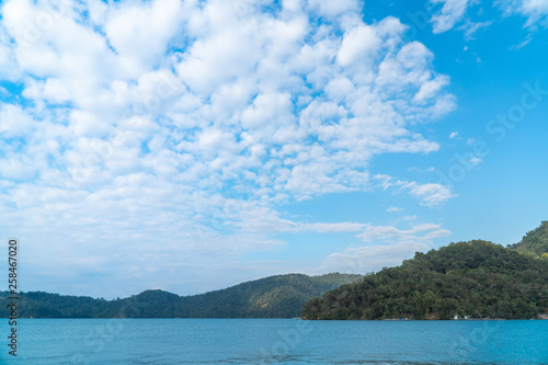 Mountains landscape scene with blue sky and white clouds over green water in sun moon lake in Taipei, Taiwan