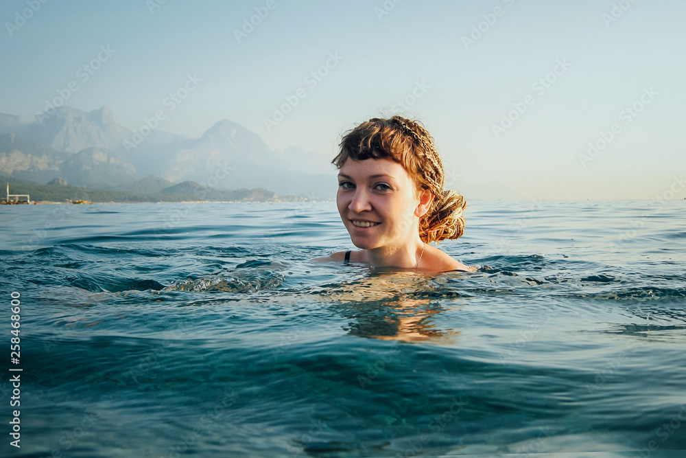 The girl swims in the blue sea. only her head is visible