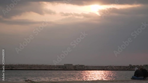 Thessaloniki / Greece 28 march 2019 :girls are  seating in the road by the sea they enjoy the good weather and the sunset