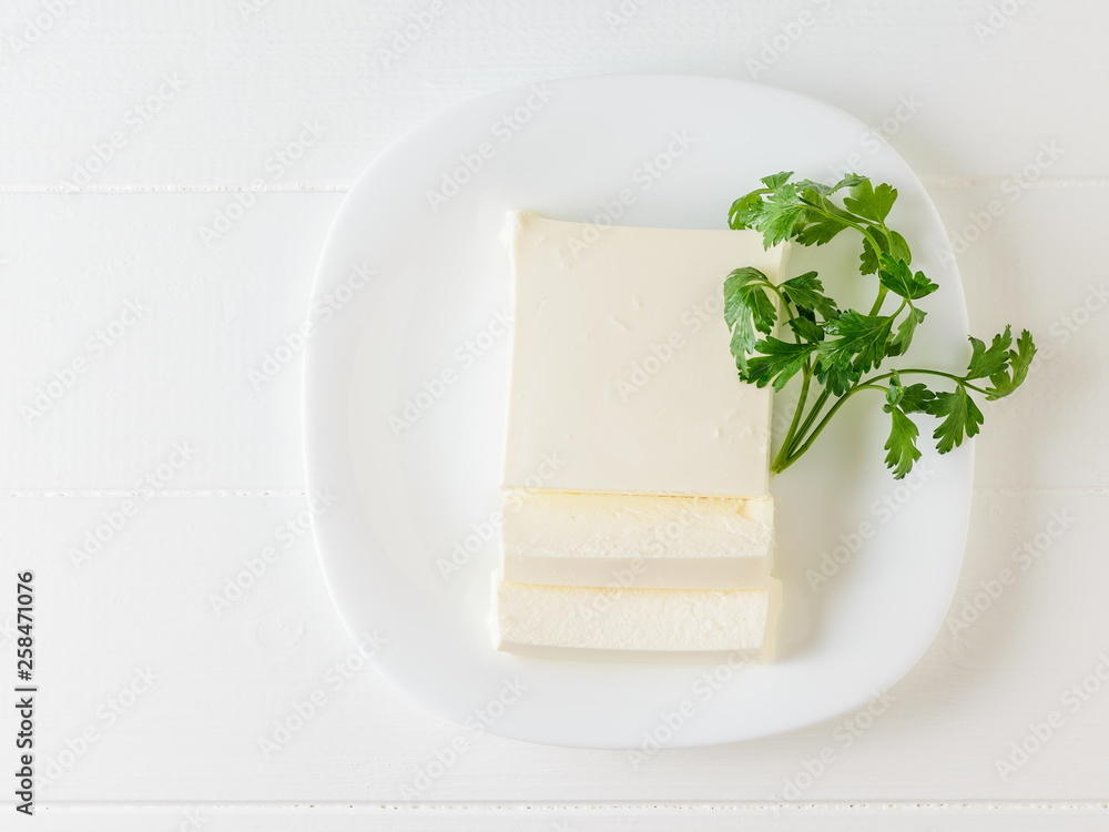 Parsley with a piece of Serbian cheese on a white plate. The view from the top. Dairy product. Parsley with a piece of Serbian cheese on a white plate. The view from the top. Dairy product.