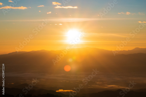 Landscape view of sunrise over the mountains and morning fog. The sun shining golden light with bokeh flare to forest, mountain and hill. Northern in Thailand.