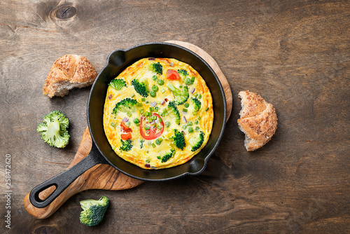 Baked omelette with green vegetables- broccoli, sweet pea and tomato in a skillet .