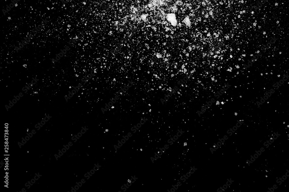 white crystalline powder on a black background. sugar dust white crystalline powder on a black background. sugar dust