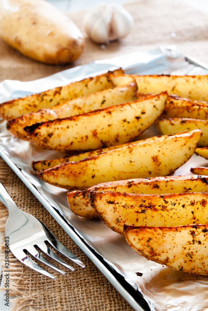 Baked potato wedges on tray - homemade organic vegetable, vegan potato wedges snack Baked potato wedges on tray - homemade organic vegetable, vegan potato wedges snack