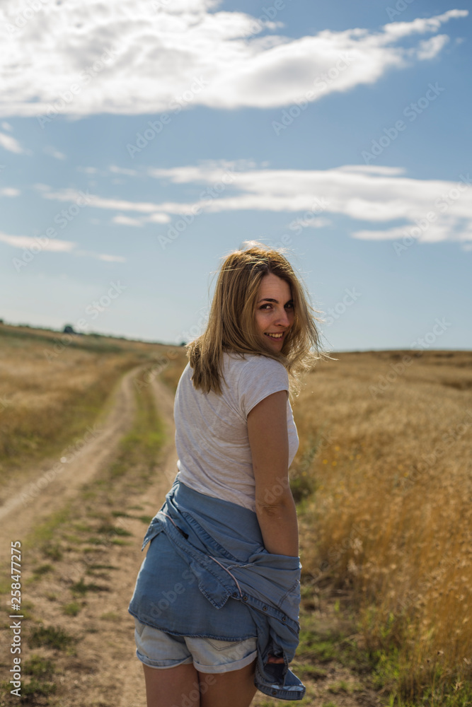 Portrait of beautiful young woman in stylish clothes posing on field