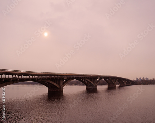 Fototapeta Naklejka Na Ścianę i Meble -  Long bridge over the river in the city. Evening view.