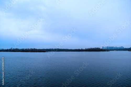 Fabulous landscape of the river and the dark dry forest. Evening.