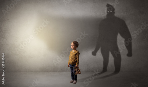 Cute kid in a room with plush on his hand and hero shadow on his background 