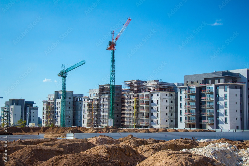 construction site with working cranes on blue sky background 