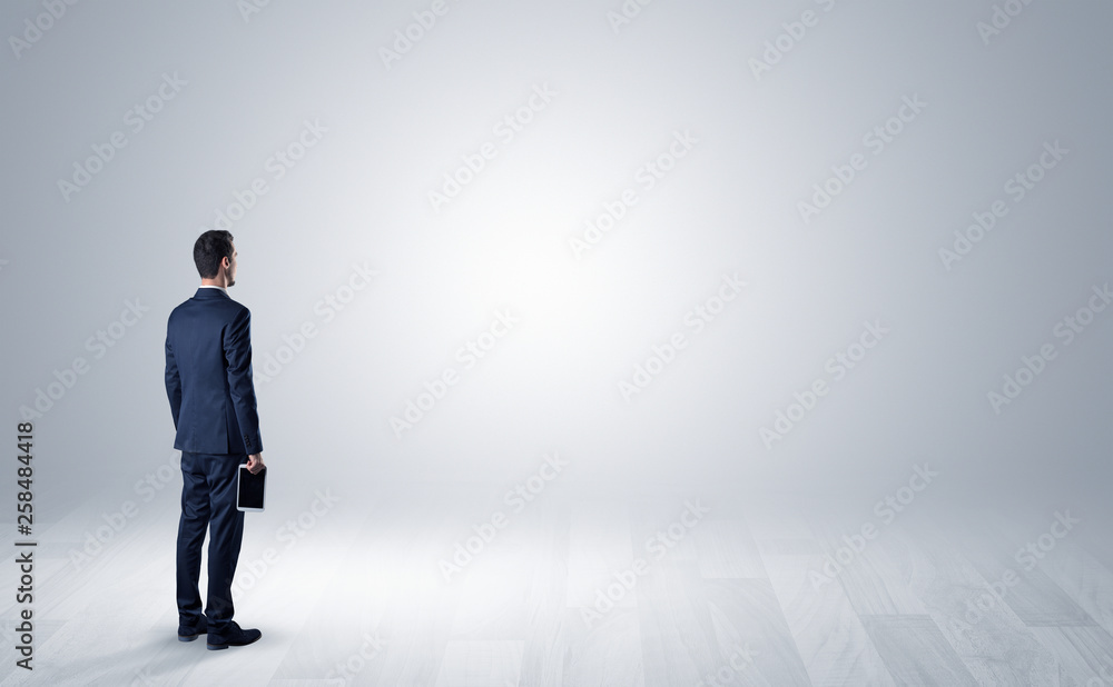 Man standing with his back in an empty room with object in his hand Man standing with his back in an empty room with object in his hand