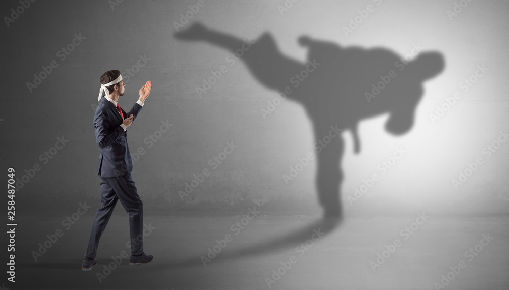 Fototapeta premium Businessman fighting with his strong karate man shadow 