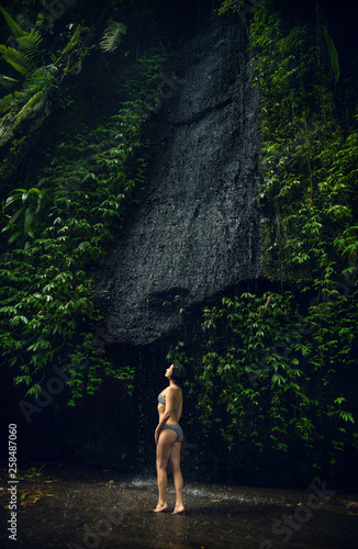 Waterfall Tukad Cepung. Waterfall in Bali. The gorge. A girl in a bathing suit at the waterfall Travel. 