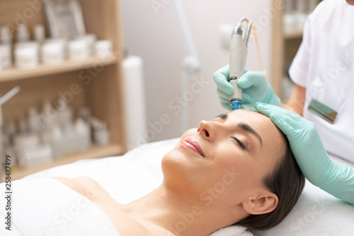 Pleased woman having her eyes closed during the dermabrasion