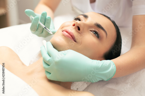 Close up of woman smiling during the injection in beauty salon