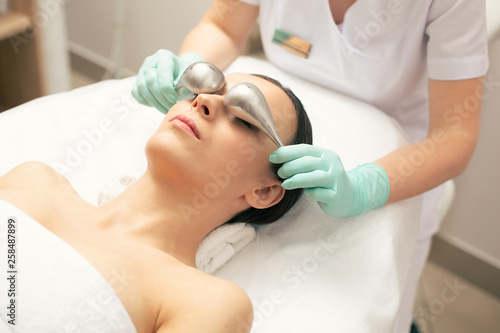 Woman with bare shoulders having cryo-sticks above her eyes