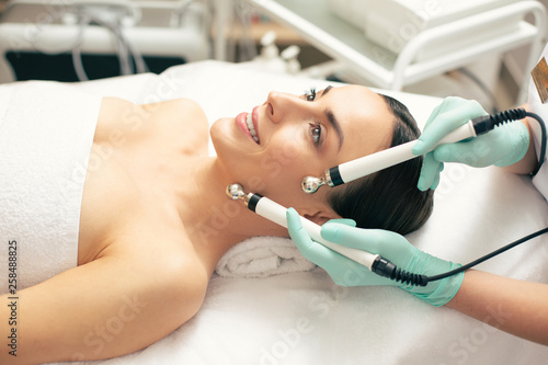 Side view of the smiling lady undergoing modern microcurrent therapy