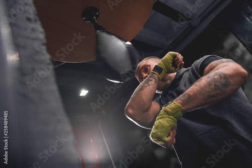 Let's get ready to rumble. Arm workout, professional young boxer with green hands wraps hitting punching speed bag in boxing gym photo