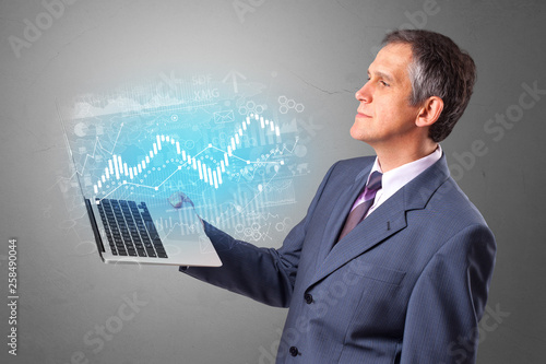 Man holding laptop projecting financial information, diagrams and charts 