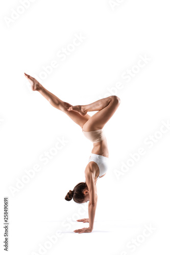 Beautiful young woman working out in studio. Handstand isolated.
