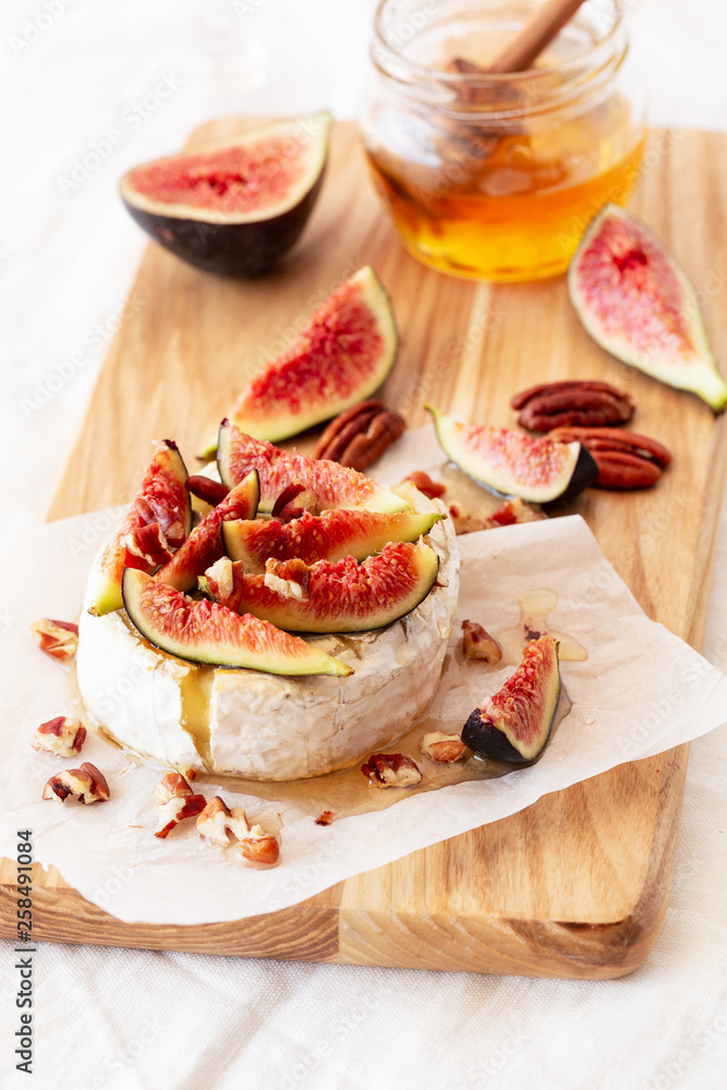 Camembert cheese with honey, figs, nuts on a wooden board Camembert cheese with honey, figs, nuts on a wooden board