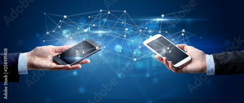 Close up of two hands holding smartphones and sharing business data