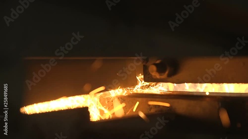Heavy flat metallic plate put on a machine tool in a dark workshop with spakles