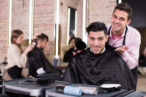 Hairdresser finished haircut of pleased man client