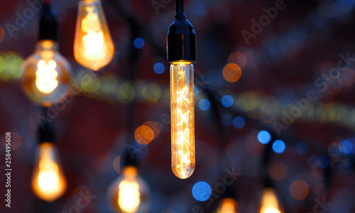 Lights background. Lit bulbs in the dark, garlands. Decorative outdoor string lights hanging in the street at night, panoramic view