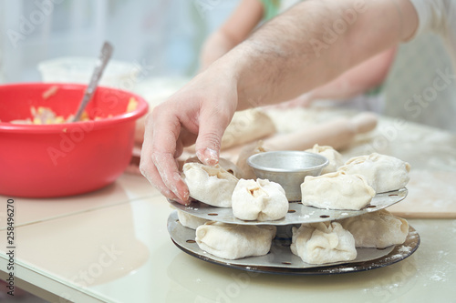 Uzbek national food manta, like dumplings, on a special steamer, a man's hand puts manta rays on a circle