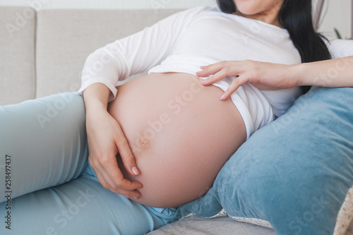 Young pregnant woman indoors. Closeup portrait of woman expecting. Beautiful female waiting for her little baby birth.