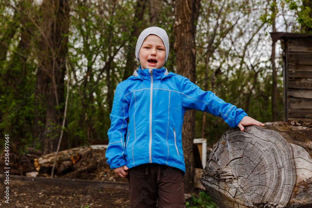 seven-year-old boy in a blue windbreake shouts of joy in the spring seven-year-old boy in a blue windbreake shouts of joy in the spring