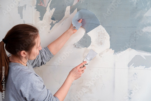 Canvas Print woman tears off Wallpaper, removing Wallpaper from the wall with a spatula, the process of updating the wall room repair