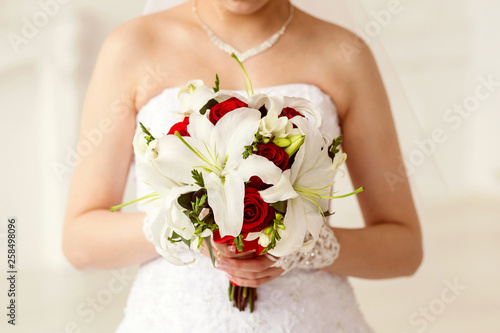 bride holding bouquet of white lilies and Red Roses