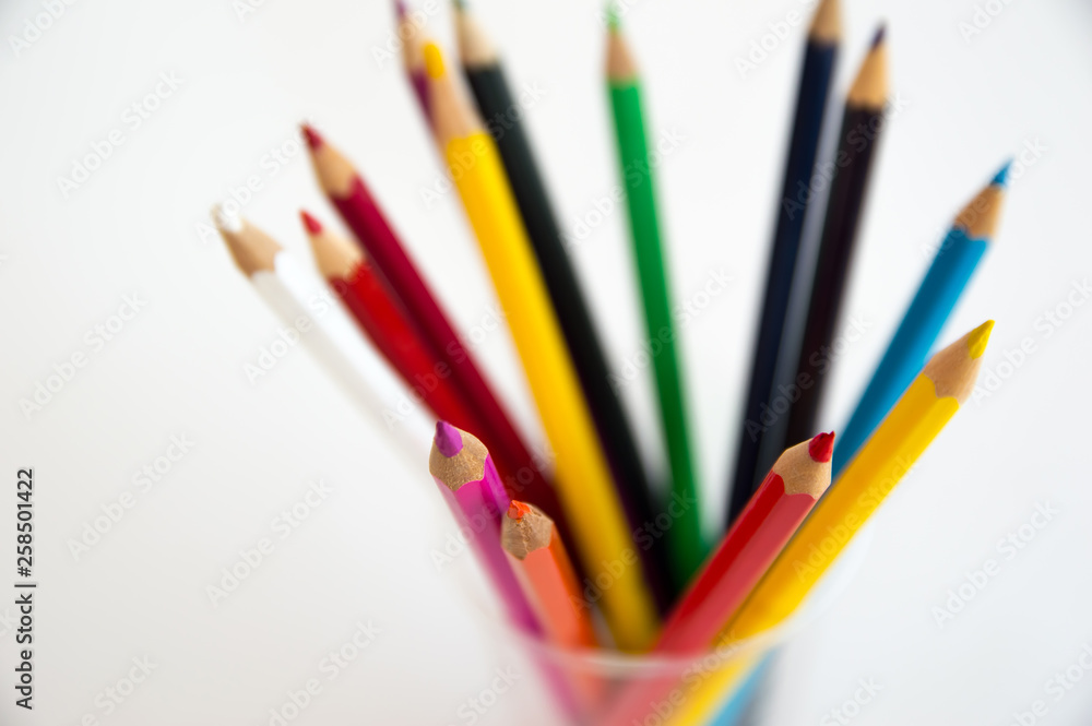 Fototapeta premium Colored wooden pencils for drawing in a glass stand on a white background. Children's multi-colored pencils for drawing.